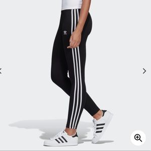 Black Adidas with three white stripes on the legs